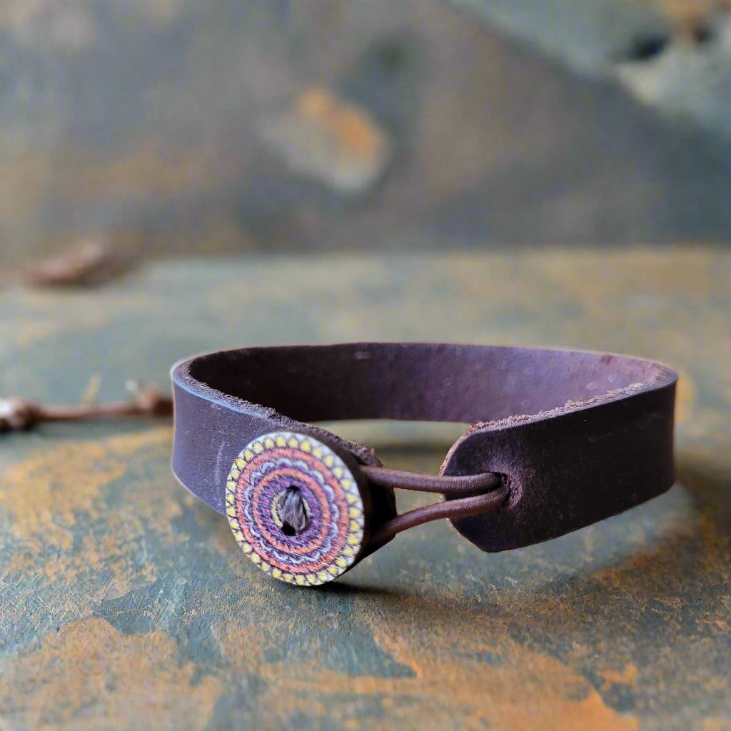 Brown leather strap with a decorative circular buckle on a wooden surface